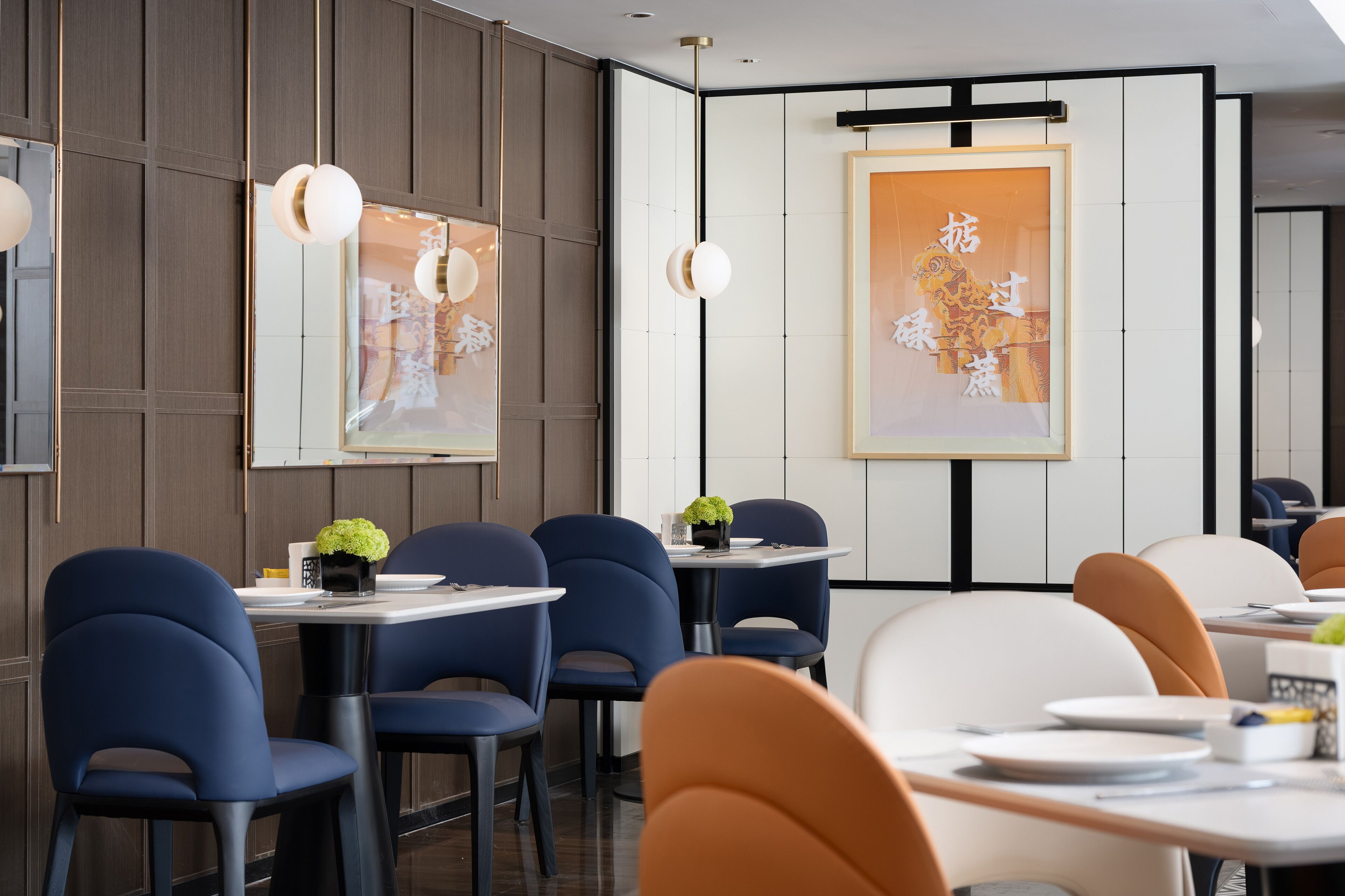 A modern dining area with dark wood paneling, blue and white chairs, and artwork on the walls.