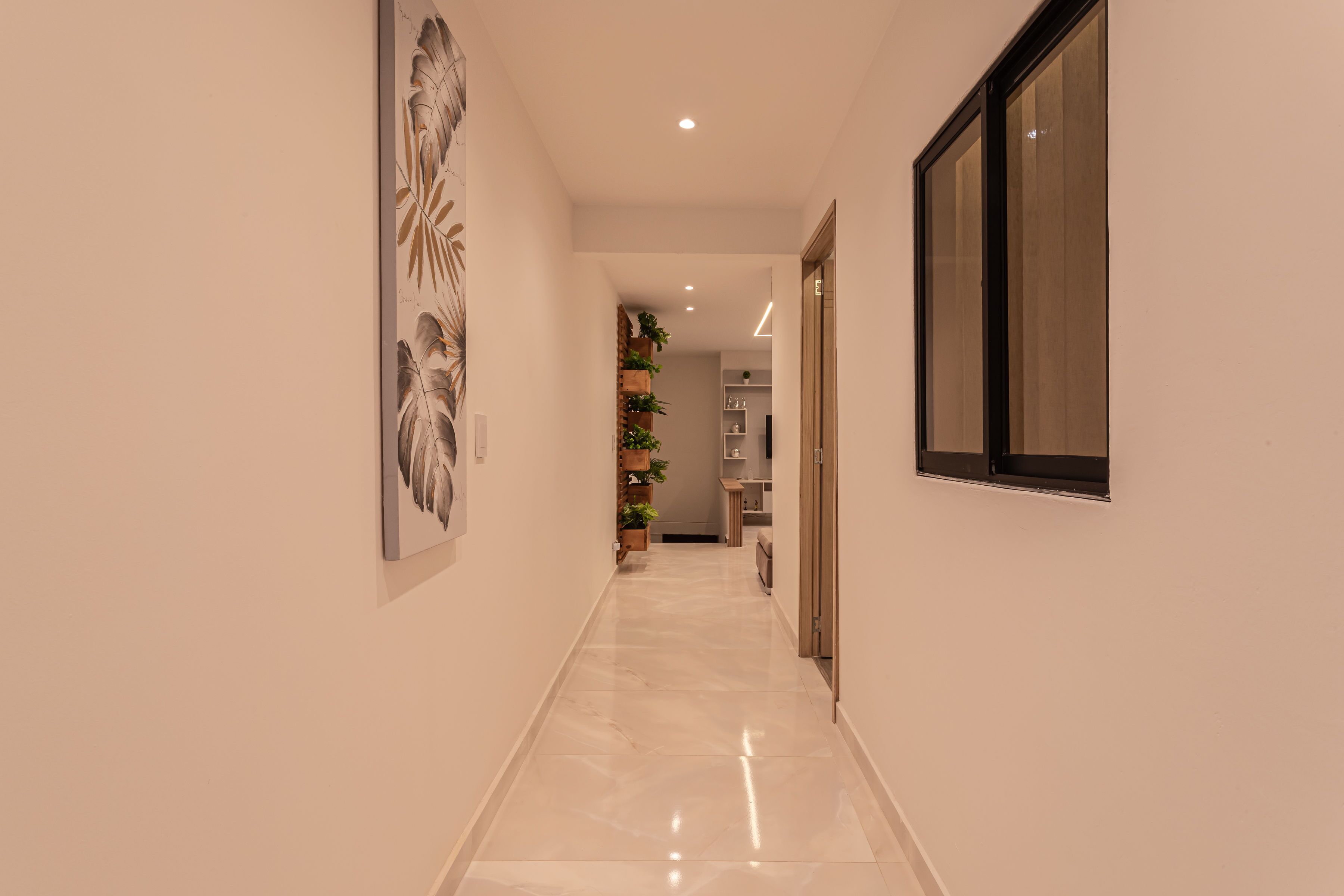 A hallway with a marble floor, a large framed artwork on the left, and a window on the right.