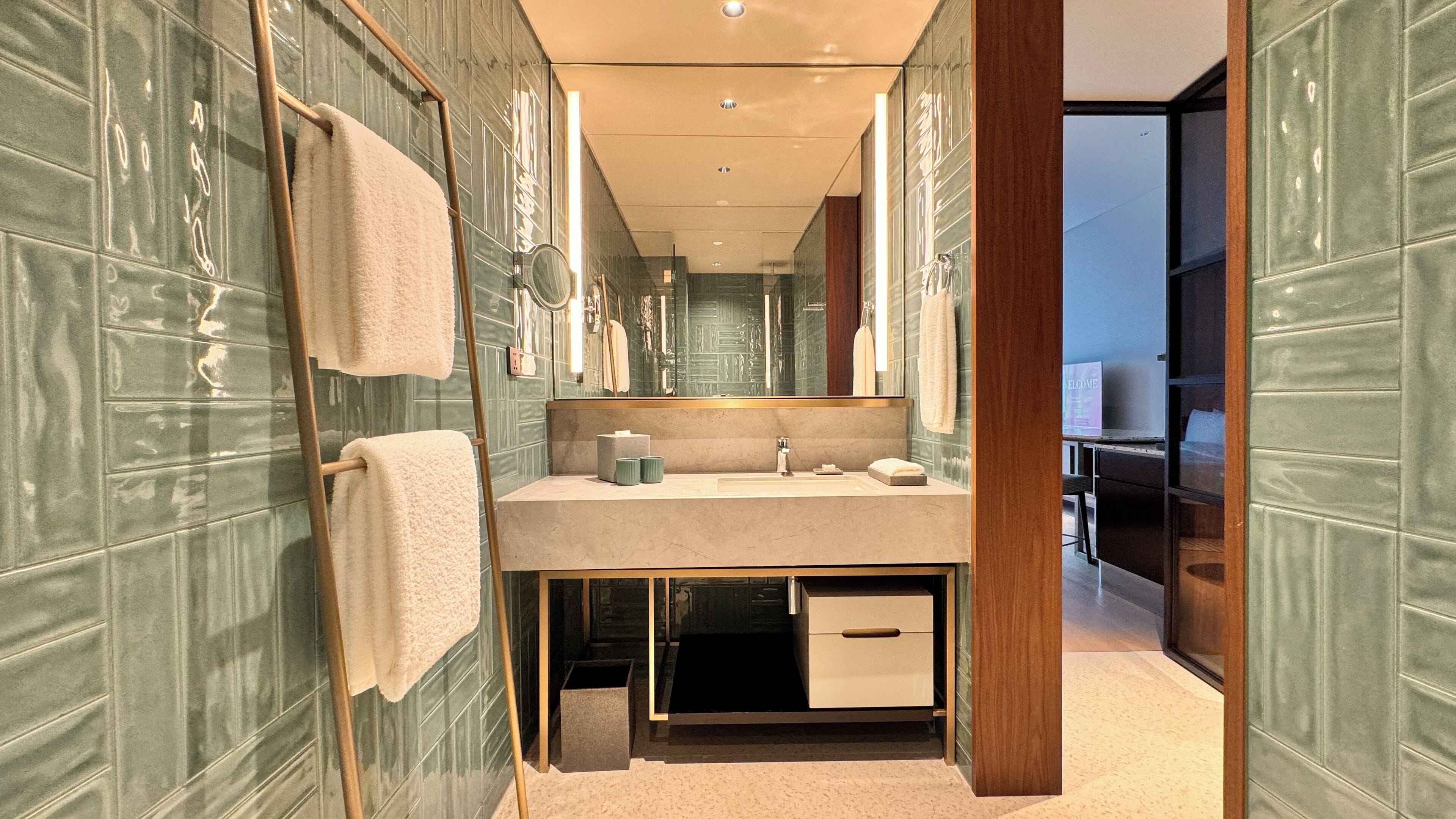 A modern bathroom with a large mirror, a sink, and a towel rack.
