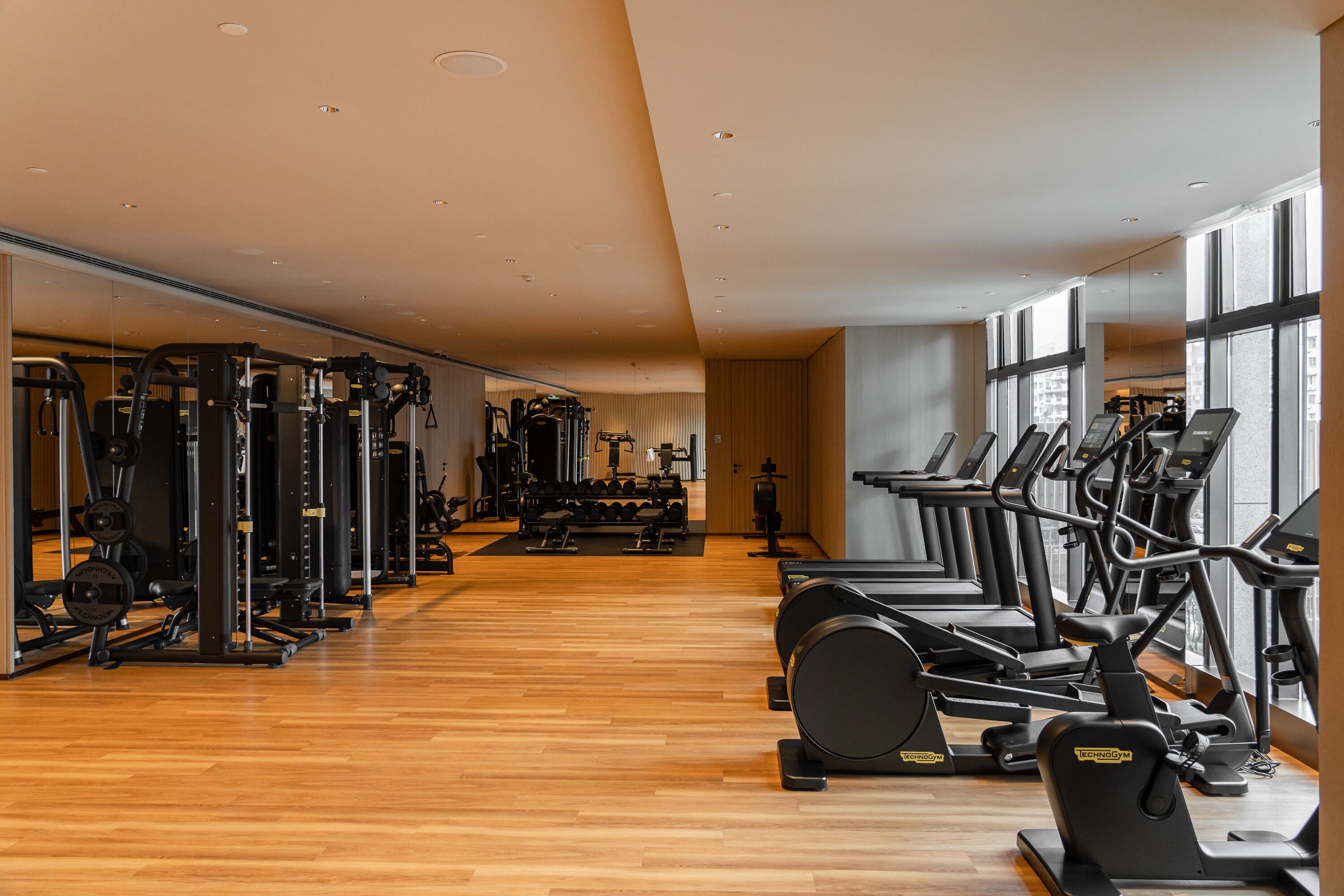 A gym with cardio machines, weightlifting equipment, and a mirrored wall.