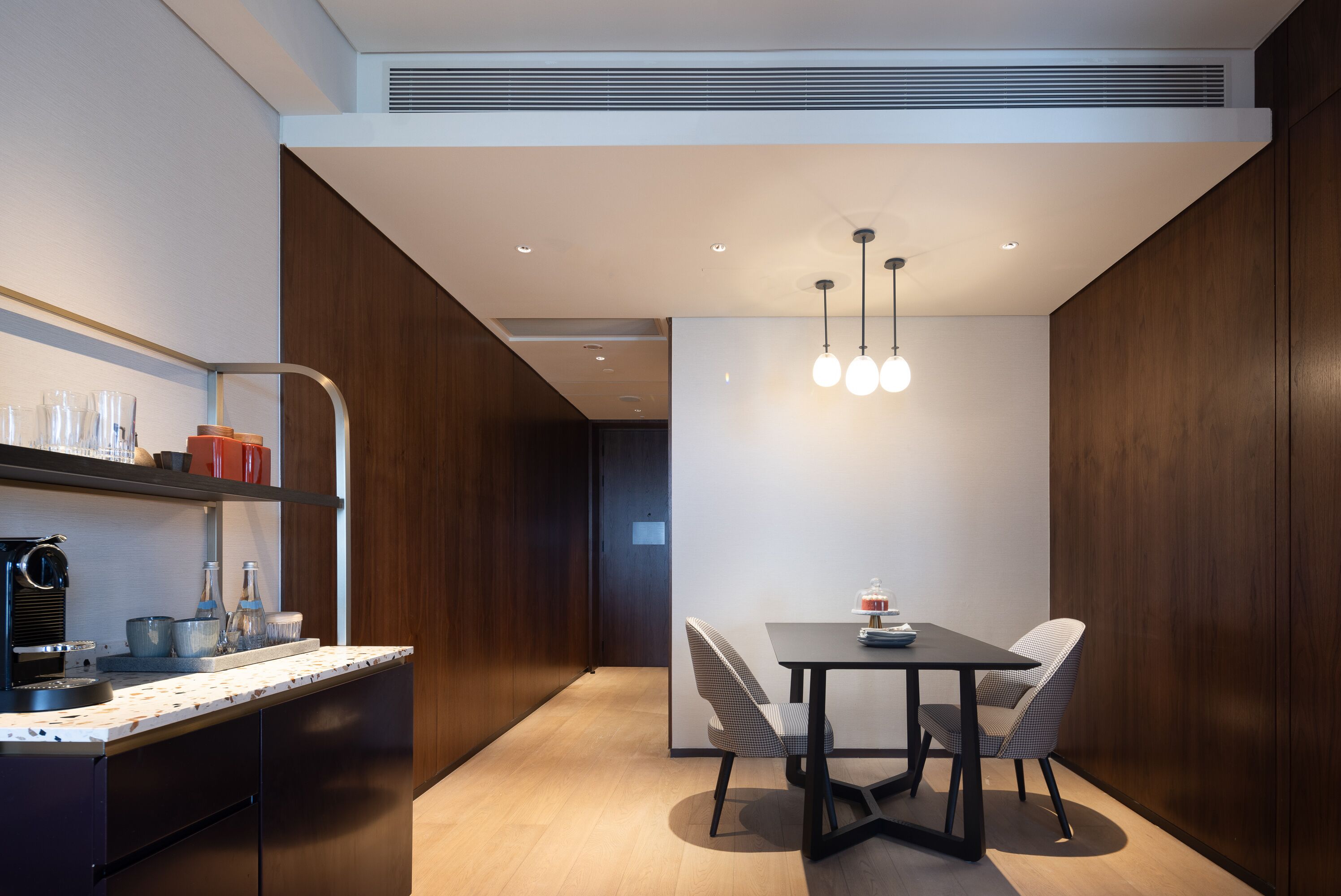 Una cocina moderna con encimera de madera, una mesa de comedor con sillas e iluminación colgante.