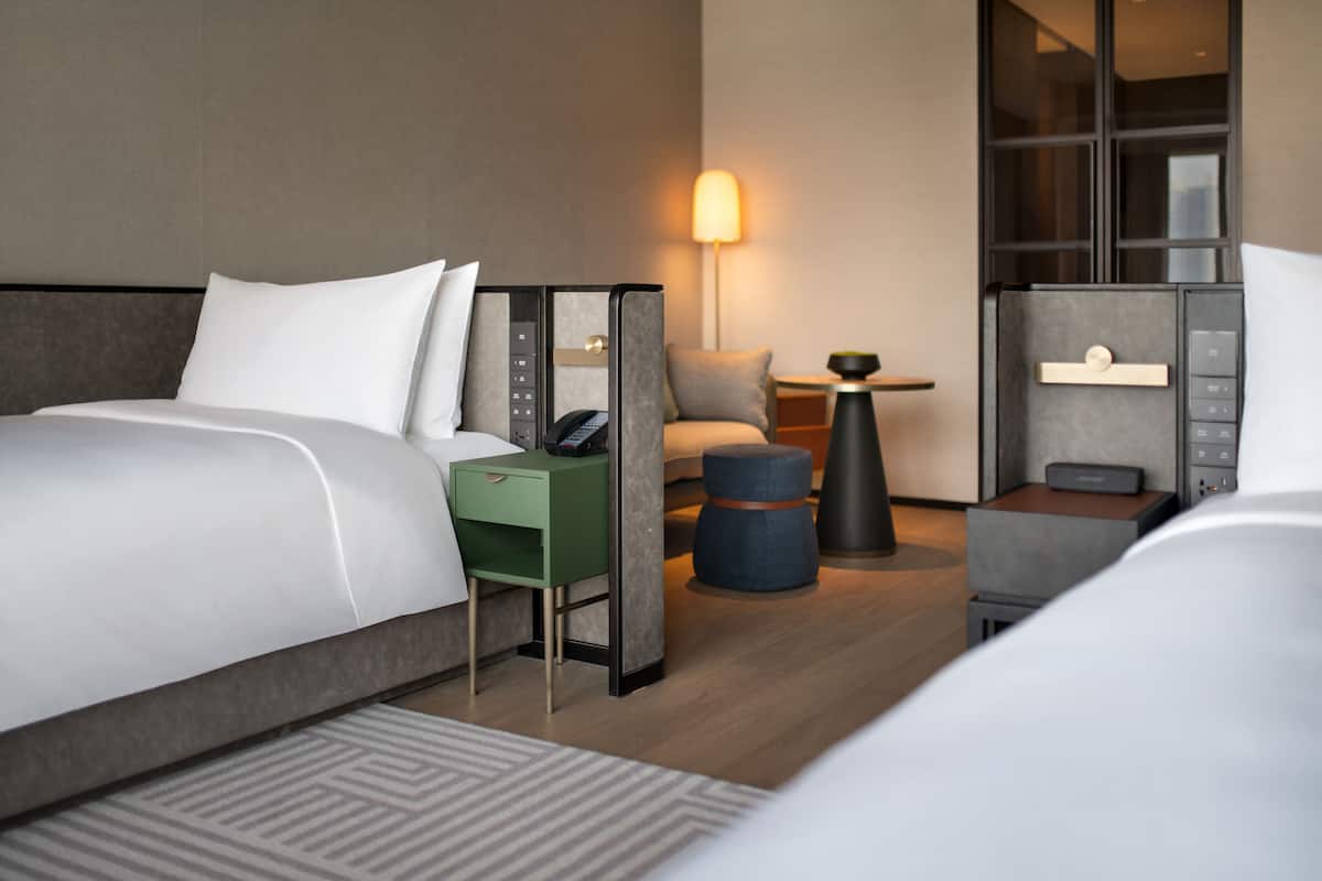 Een hotelkamer met een groot bed, een bureau, een stoel, een bijzettafeltje en een lamp.