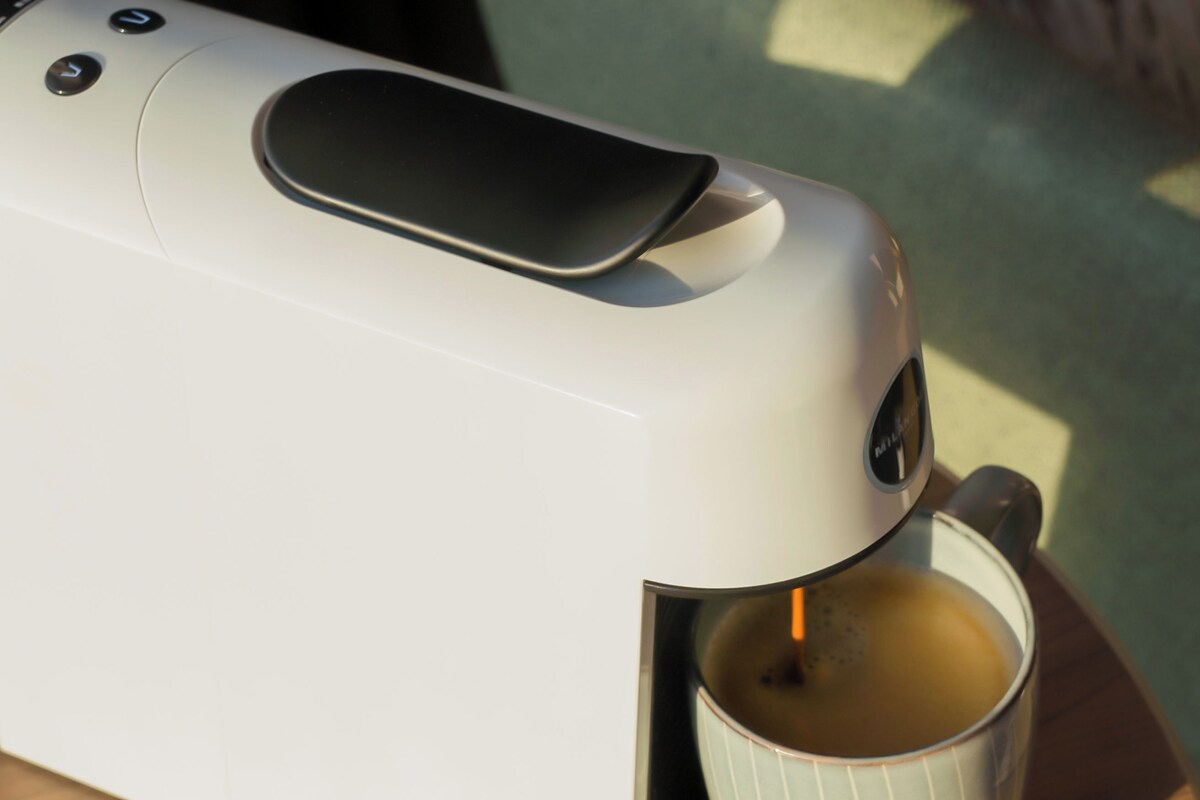 A coffee maker with a cup of coffee, a control panel, and a power button.