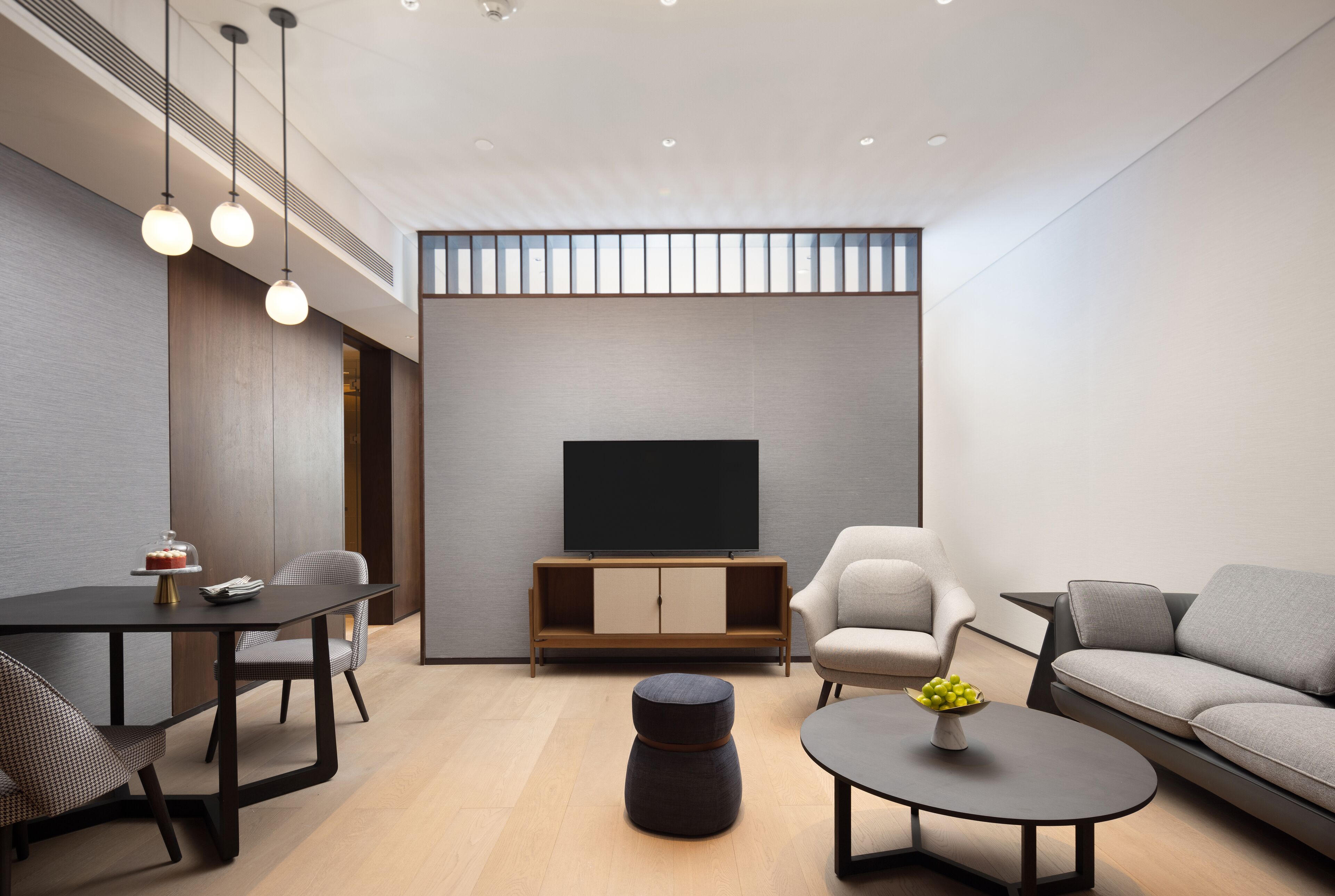 A modern living room with a flat-screen TV, a dining table with chairs, a sofa, and a coffee table.