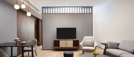 A modern living room with a flat-screen TV, a dining table with chairs, a sofa, and a coffee table.