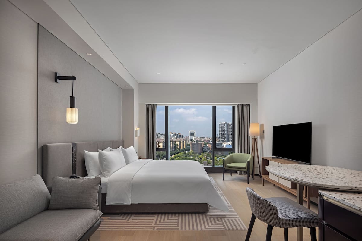 Een moderne hotelkamer met een groot bed, een bank, een eettafel en een televisie.