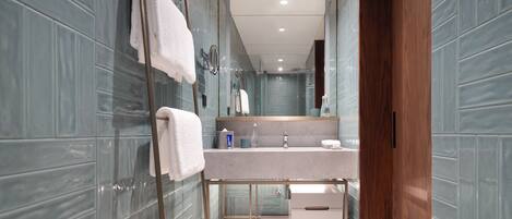 A modern bathroom with a glass shower enclosure, a vanity with a mirror, and a wooden door.