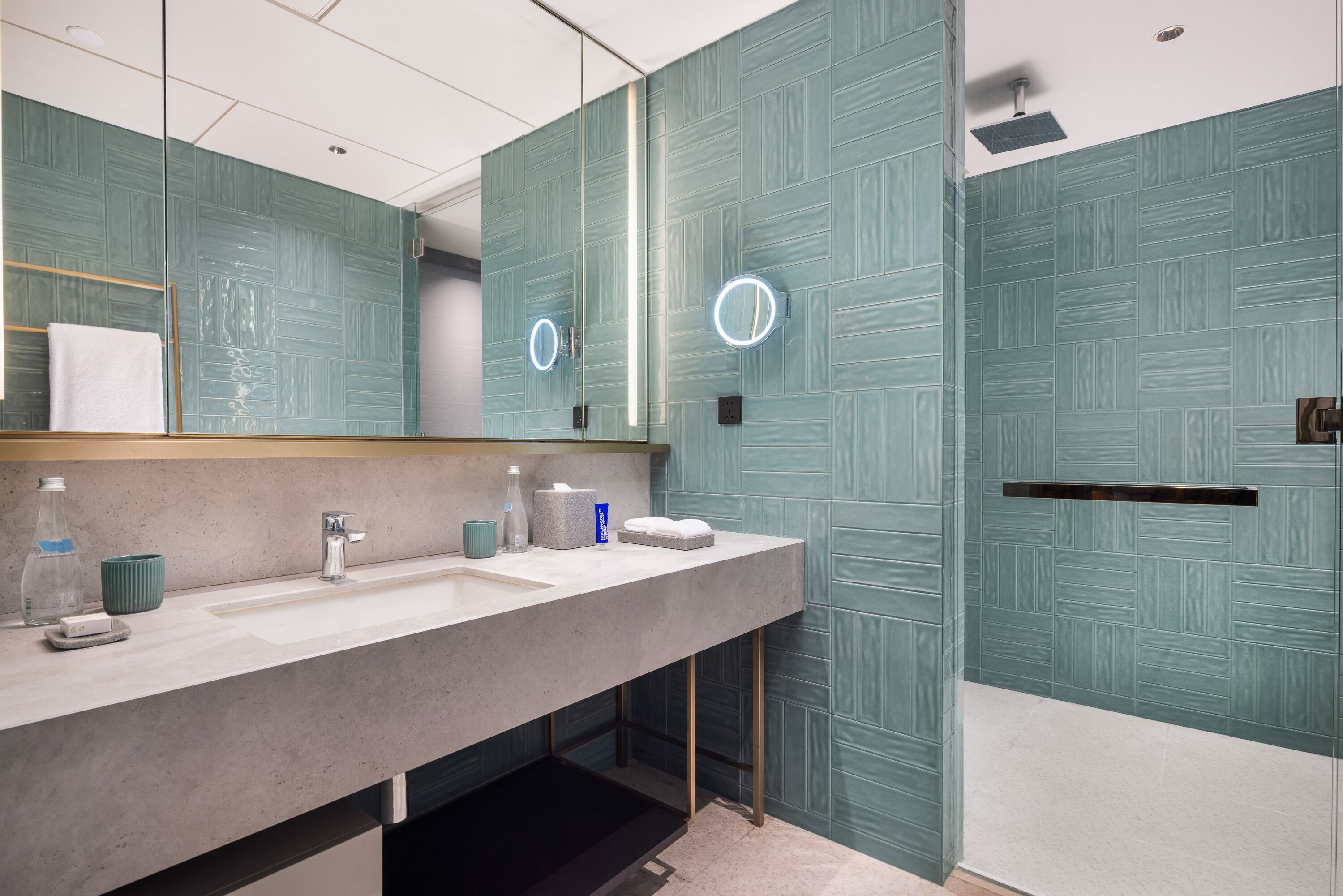 Une salle de bain moderne avec un grand miroir, deux lavabos et un espace douche.