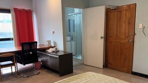 Une chambre d’hôtel équipée d’un bureau, d’une chaise et d’un lit avec une couvre-lit à motifs.