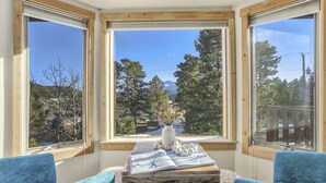 Una stanza con ampie finestre, un tavolo in legno con una rivista e due sedie blu.
