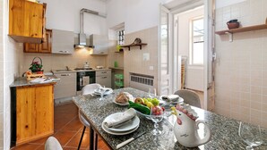 A kitchen with wooden cabinets, a granite countertop, and a dining area with a table set for two.