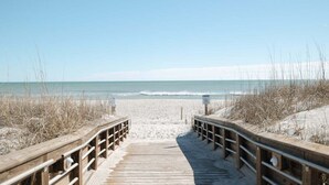 Una passerella in legno che conduce a una spiaggia sabbiosa con vista libera sull'oceano.