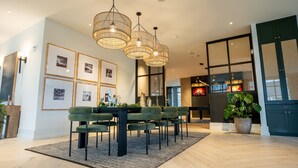 A modern dining area with a black table, green upholstered chairs, and a patterned rug. - Luxurious, New Apt | Pool | Long Stays (Athens)