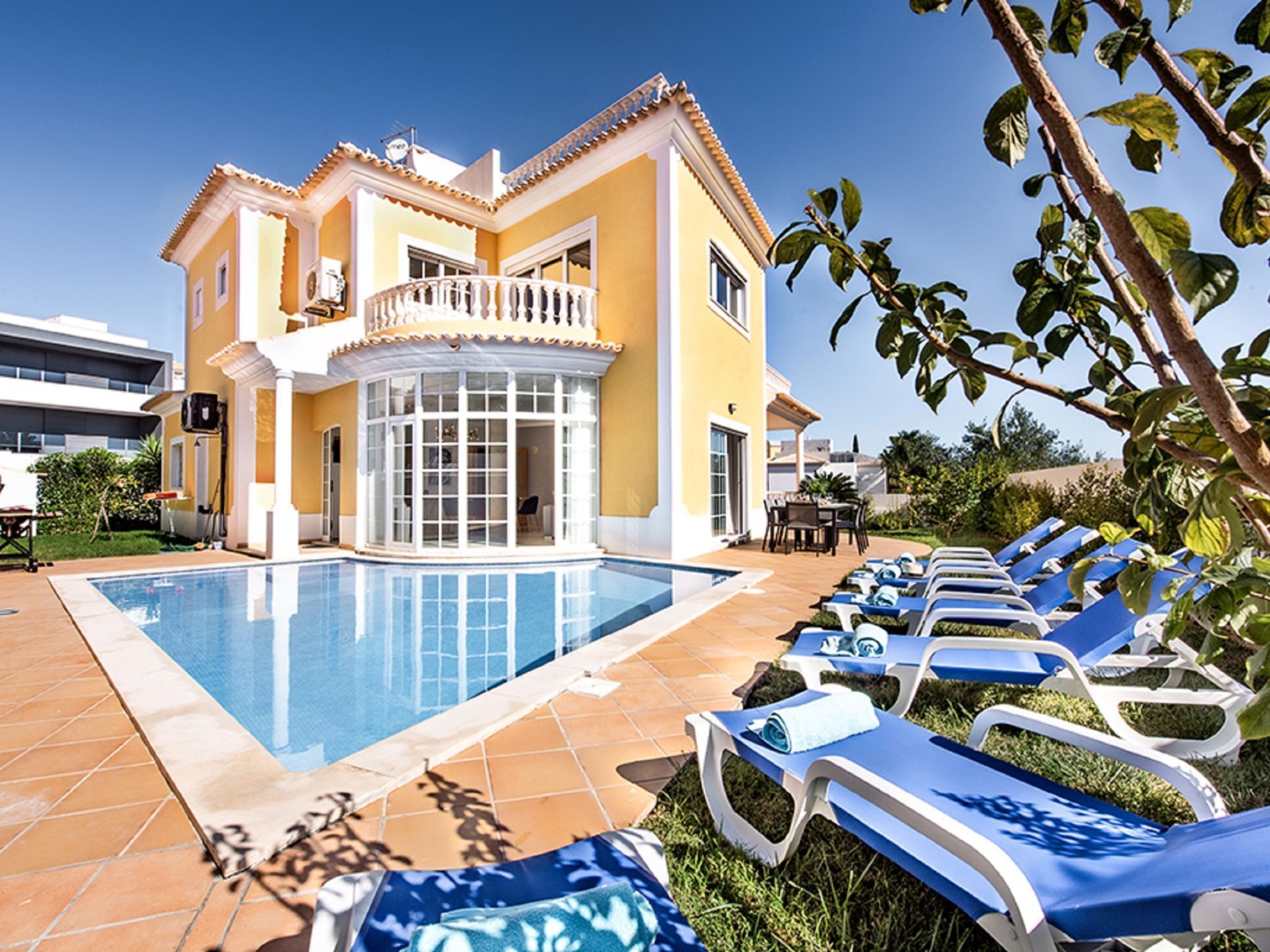 A yellow building with a pool and lounge chairs.