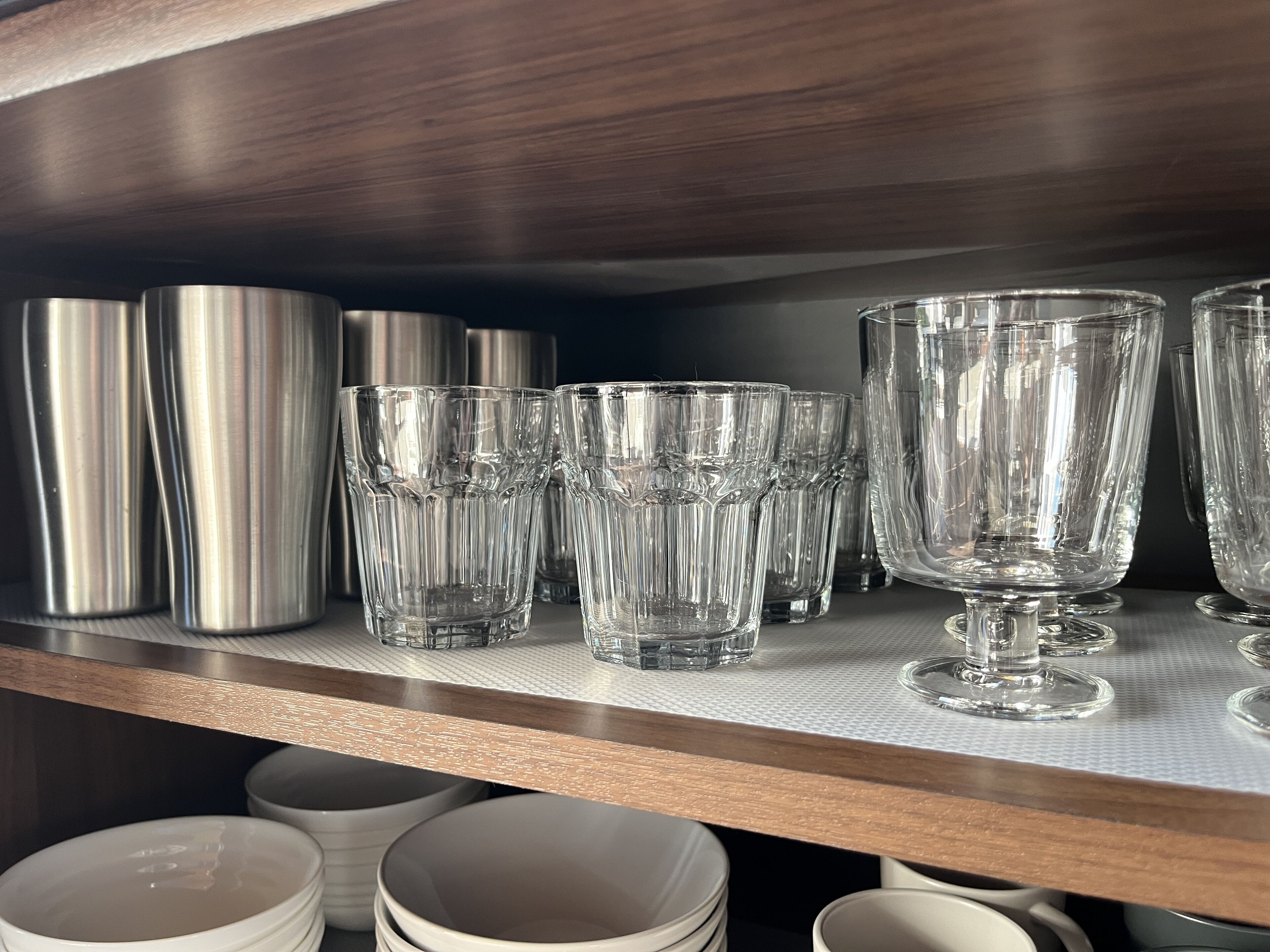 A shelf with various glassware including tumblers, glasses, and a large bowl.