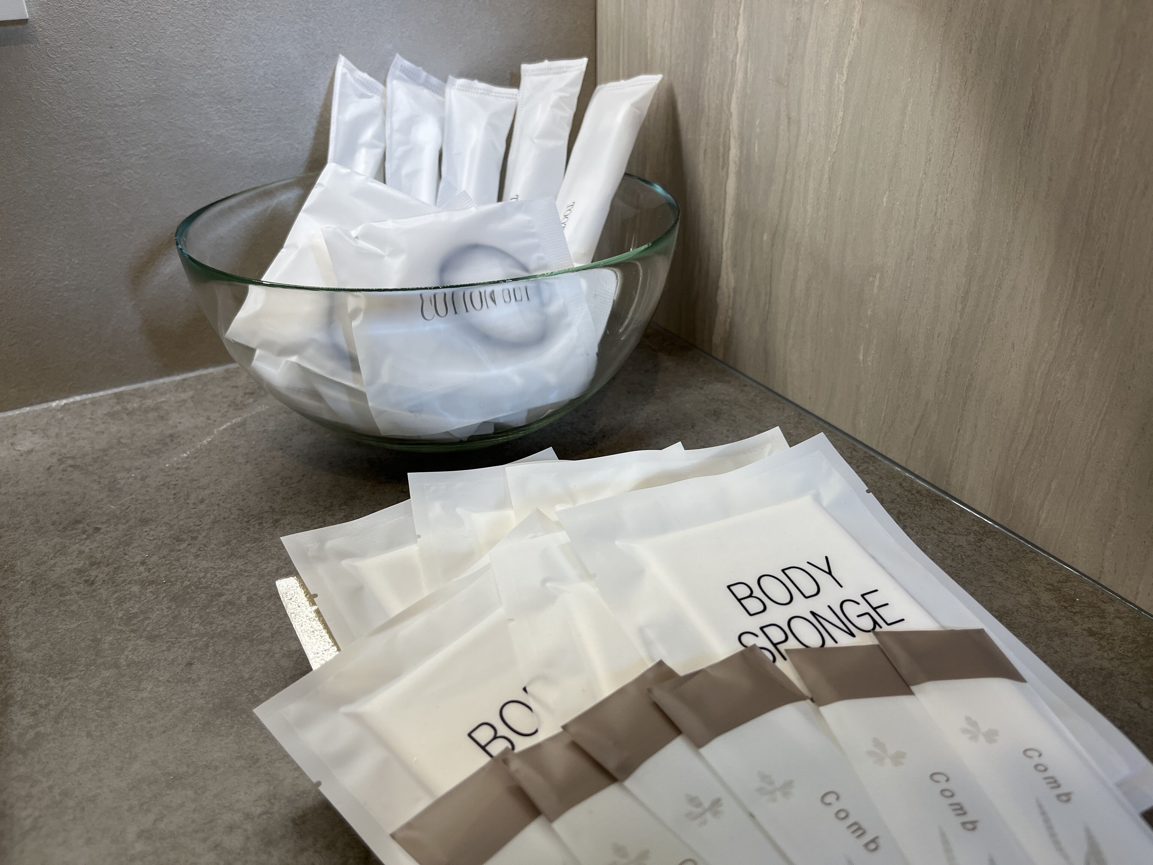 Eine Glaskasse mit Wattepads und einer Schale gefüllt mit Körperponge-Verpackungen.