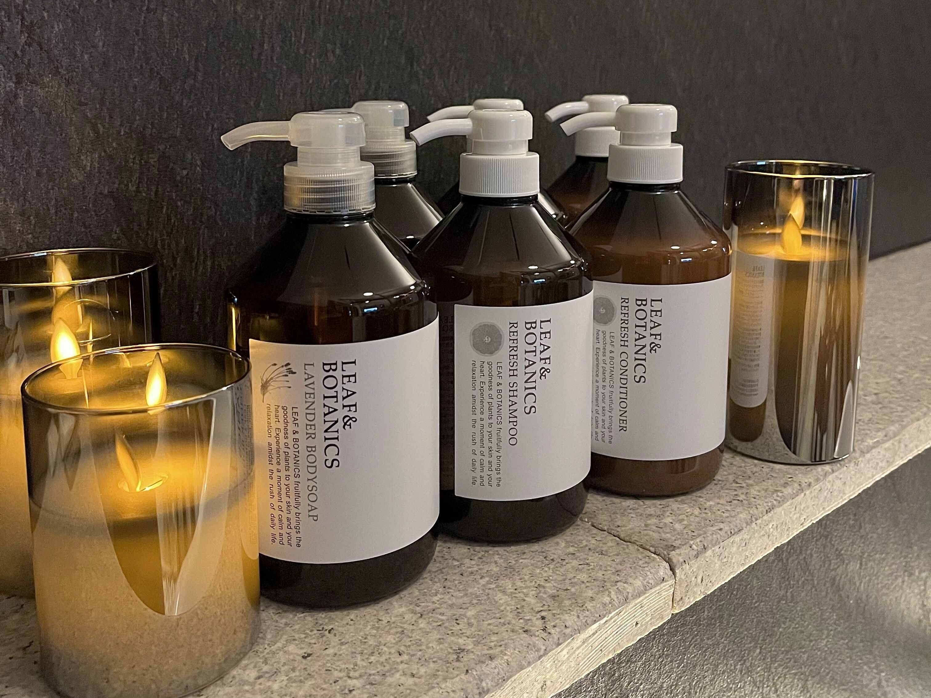 Un estante con varias botellas de productos Leaf & Botanics y velas.