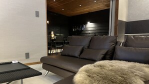 A modern living room with a dark brown sofa, a small black table, and a fluffy round pillow. - Villa CORTILE (Awaji)