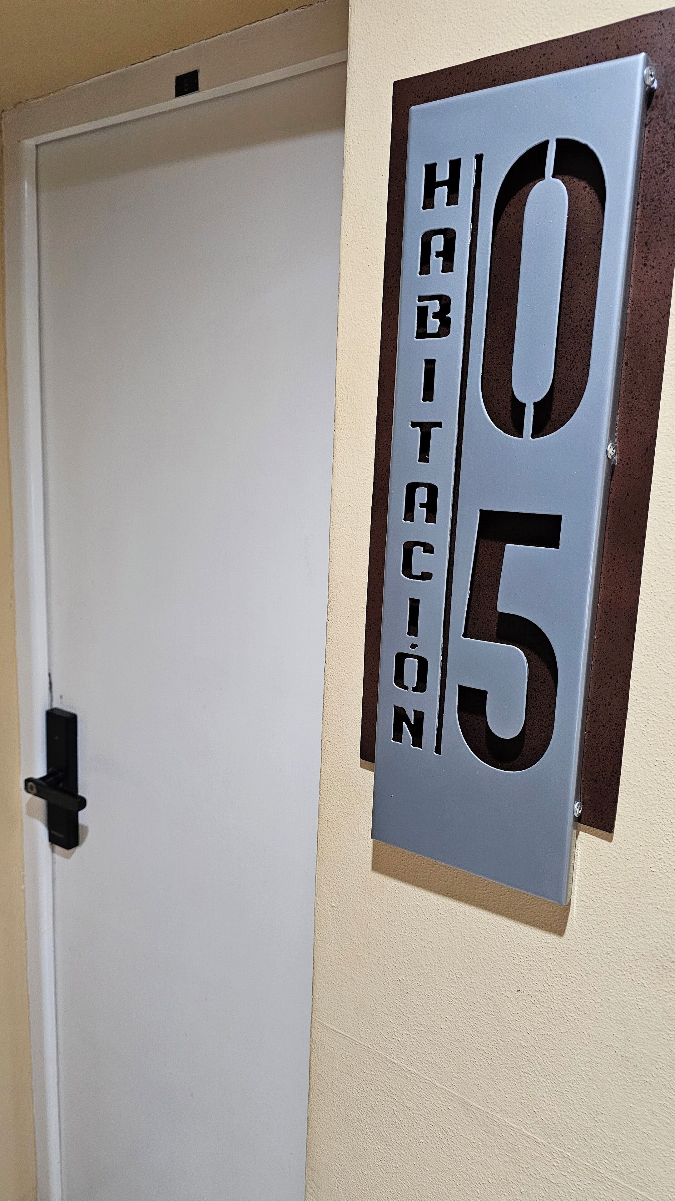 A door with a metal plaque indicating room number 05 and the word "HABITACION" (meaning "apartment" in Spanish).