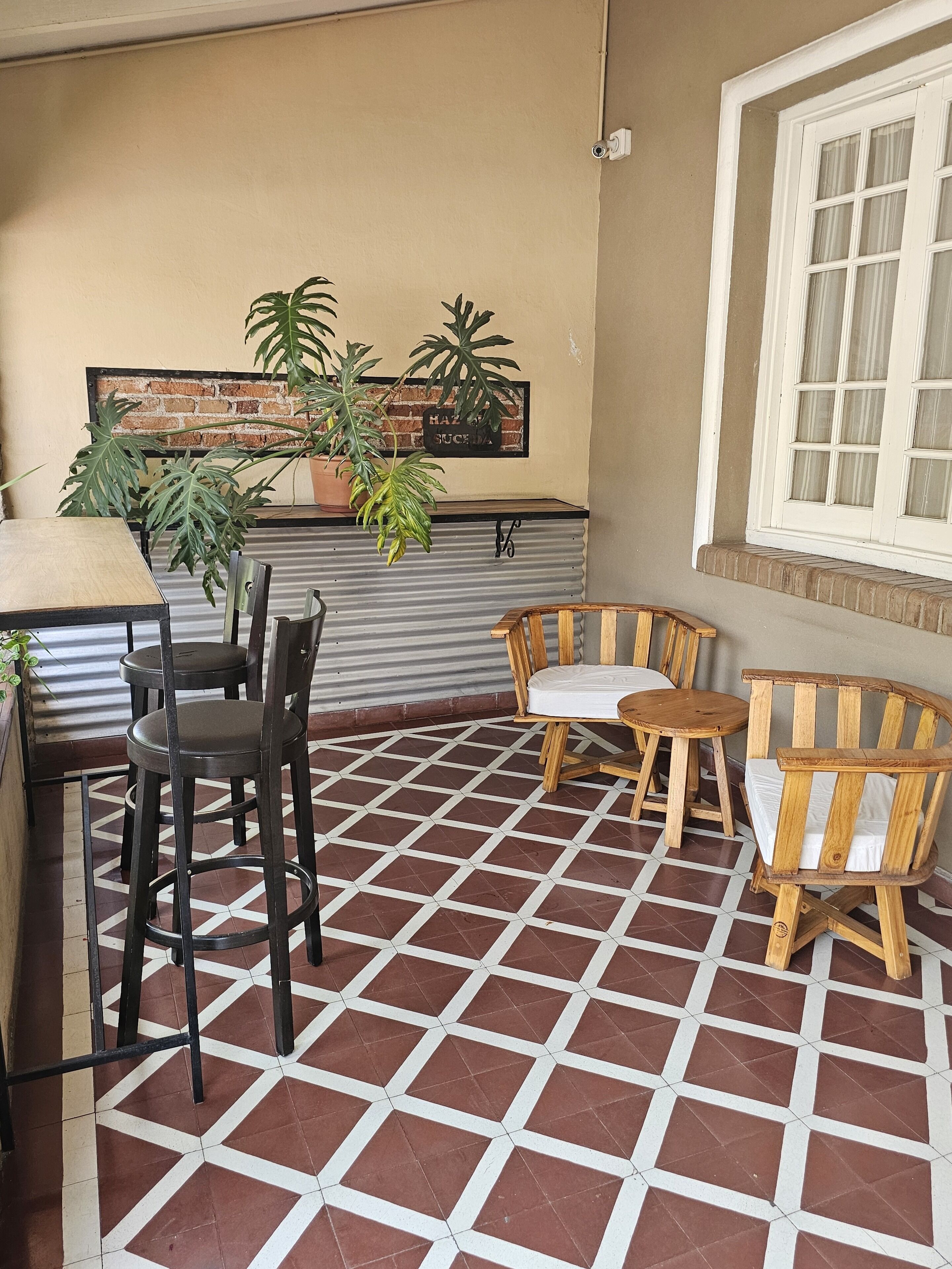 A patio area with a table and chairs, potted plants, and a brick wall with a sign.