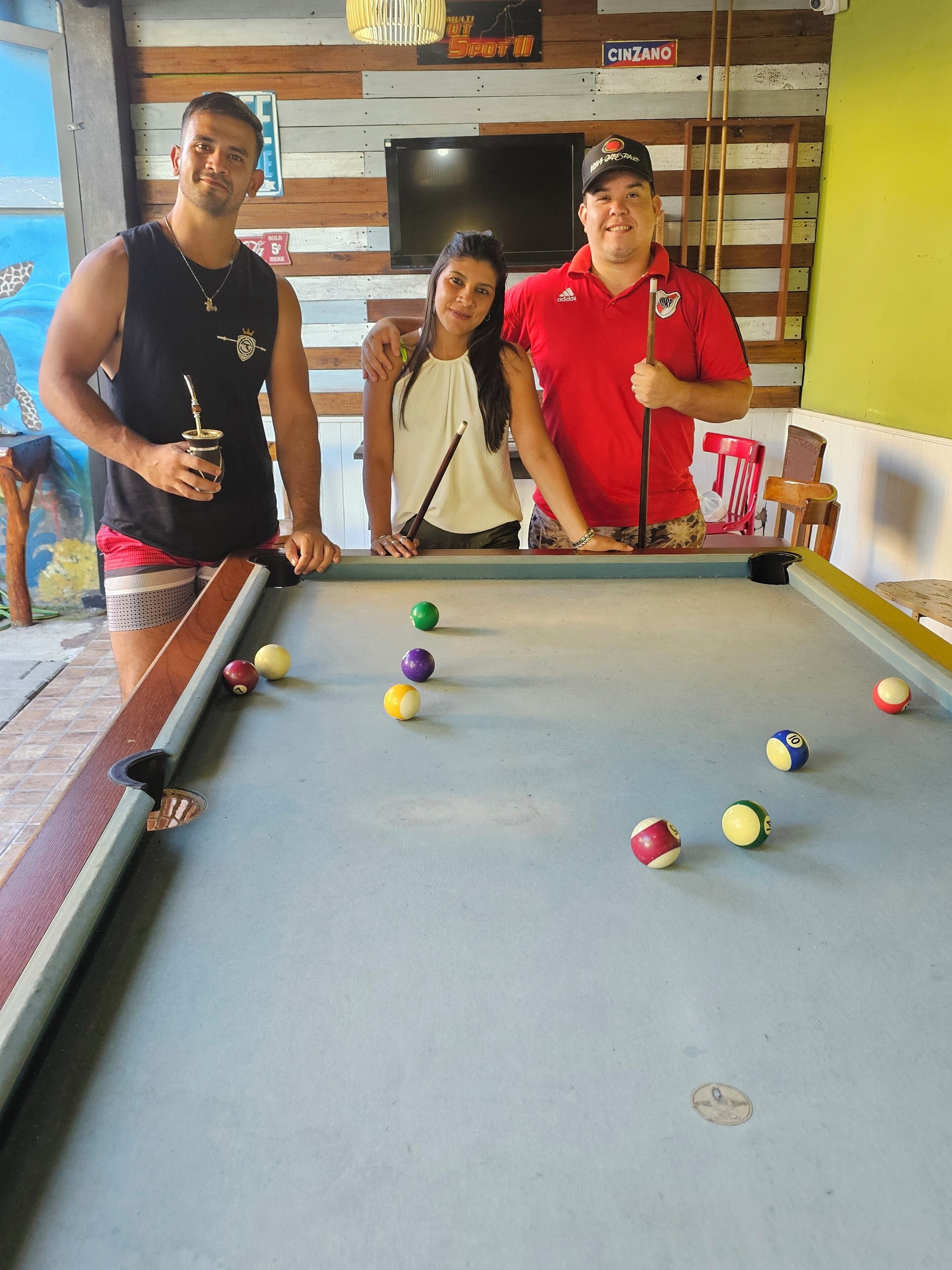A pool table with billiard balls and a person holding a cue stick.