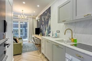 A modern kitchen with grey cabinets, a built-in oven, and a large window. - Boutique Downtown Studio with Balcony 1 (Zagreb)