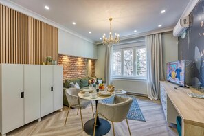 A modern kitchen with a dining area, a brick accent wall, and a large window.