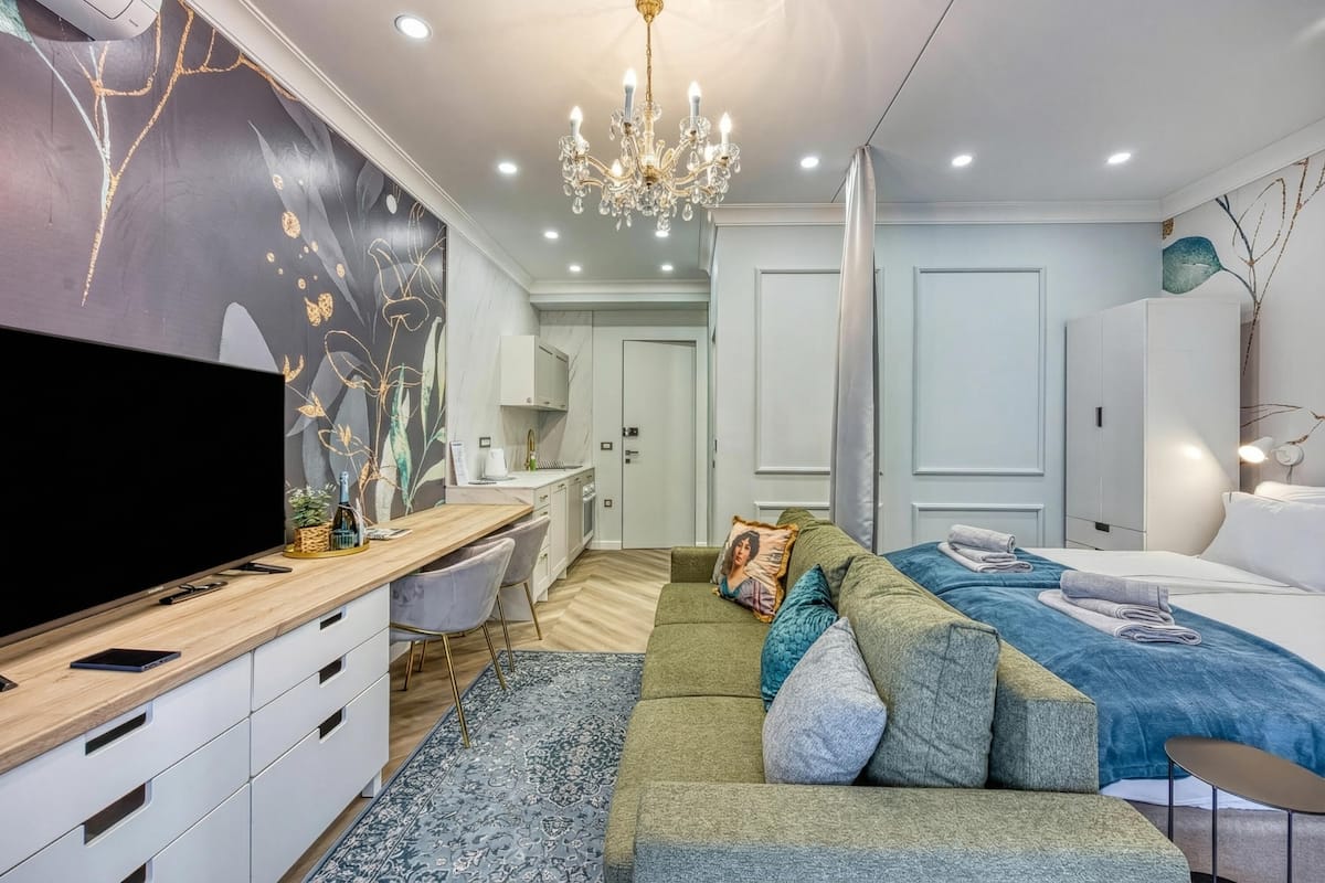 Une chambre à coucher moderne, équipée d’une télévision, d’un canapé et d’un lustre.