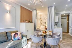 A modern living room with a sofa, a dining table set for four, and a kitchen area visible in the background. - Boutique Downtown Studio with Balcony 1 (Zagreb)