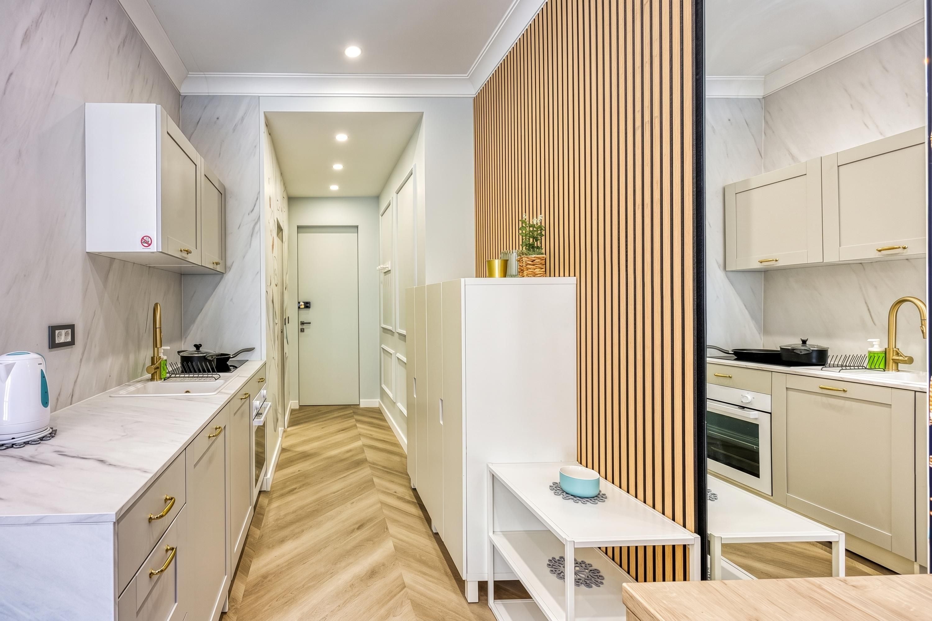 A modern kitchen with white cabinetry, a herringbone wood floor, and a central island with a blue bowl.