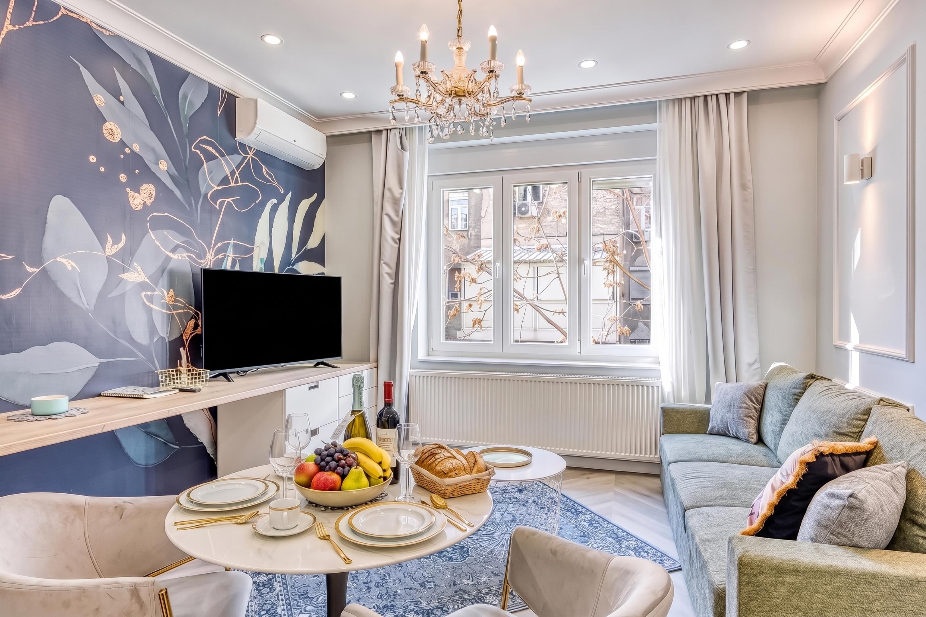Een moderne woonkamer met een flatscreen televisie, een eettafel voor twee personen en een comfortabele bank.