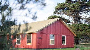 Un bâtiment rouge avec un toit en pente, une enseigne indiquant « Pinehurst House », et une allée pavée menant à l’entrée.