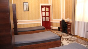 A hotel room with two wooden beds, a desk, a chair, a door, and a chandelier. - BEST GUESTHOUSE (Tashkent)