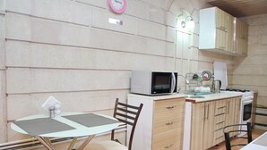 A compact kitchen with a microwave, stove, and a small dining area with a table and chairs. - BEST GUESTHOUSE (Tashkent)