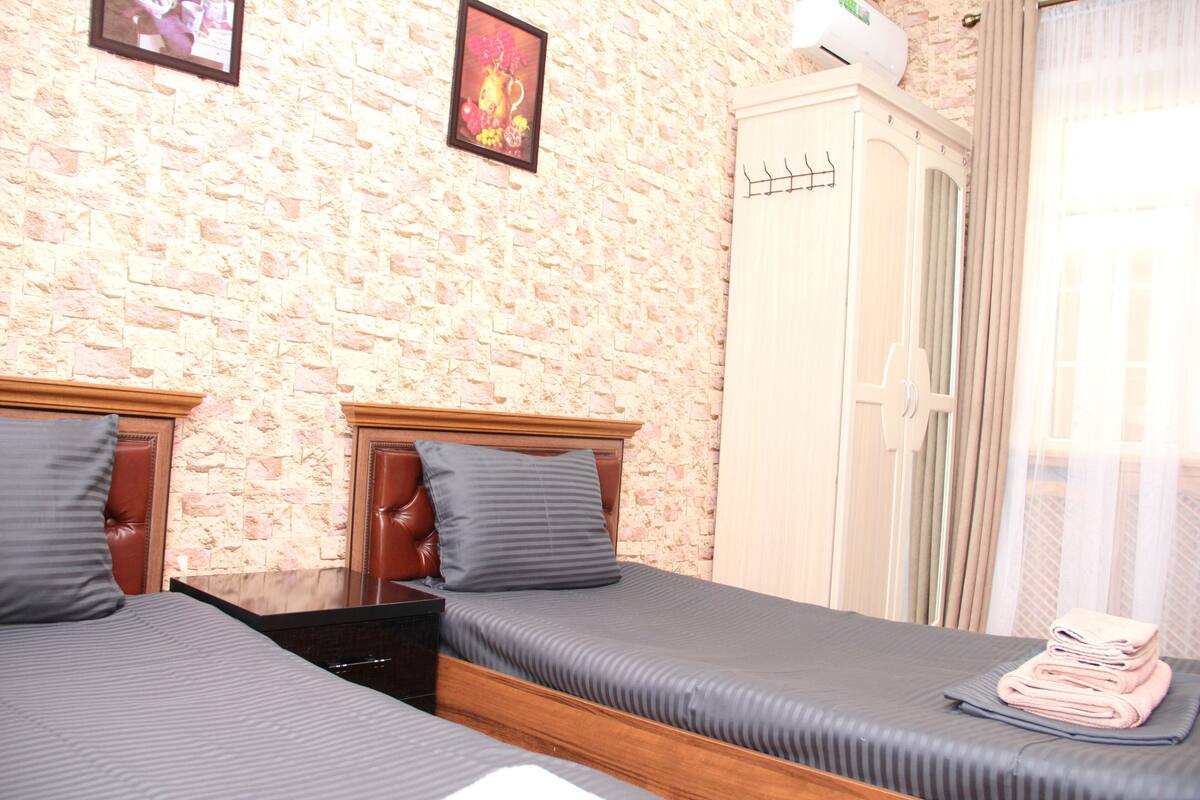 A bedroom with two beds, a wardrobe, and a wall-mounted air conditioner.