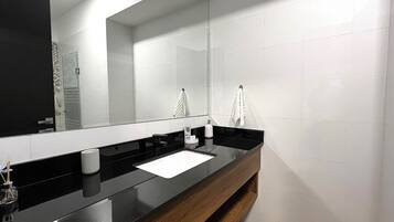 A modern bathroom with a black countertop, a mirror, and white tiles.