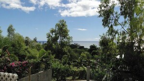 Ein Garten mit Swimmingpool, Steinmauer und Blick aufs Meer.