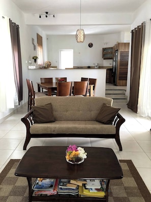 Un salon avec un canapé, une table basse et, au fond, un coin repas.