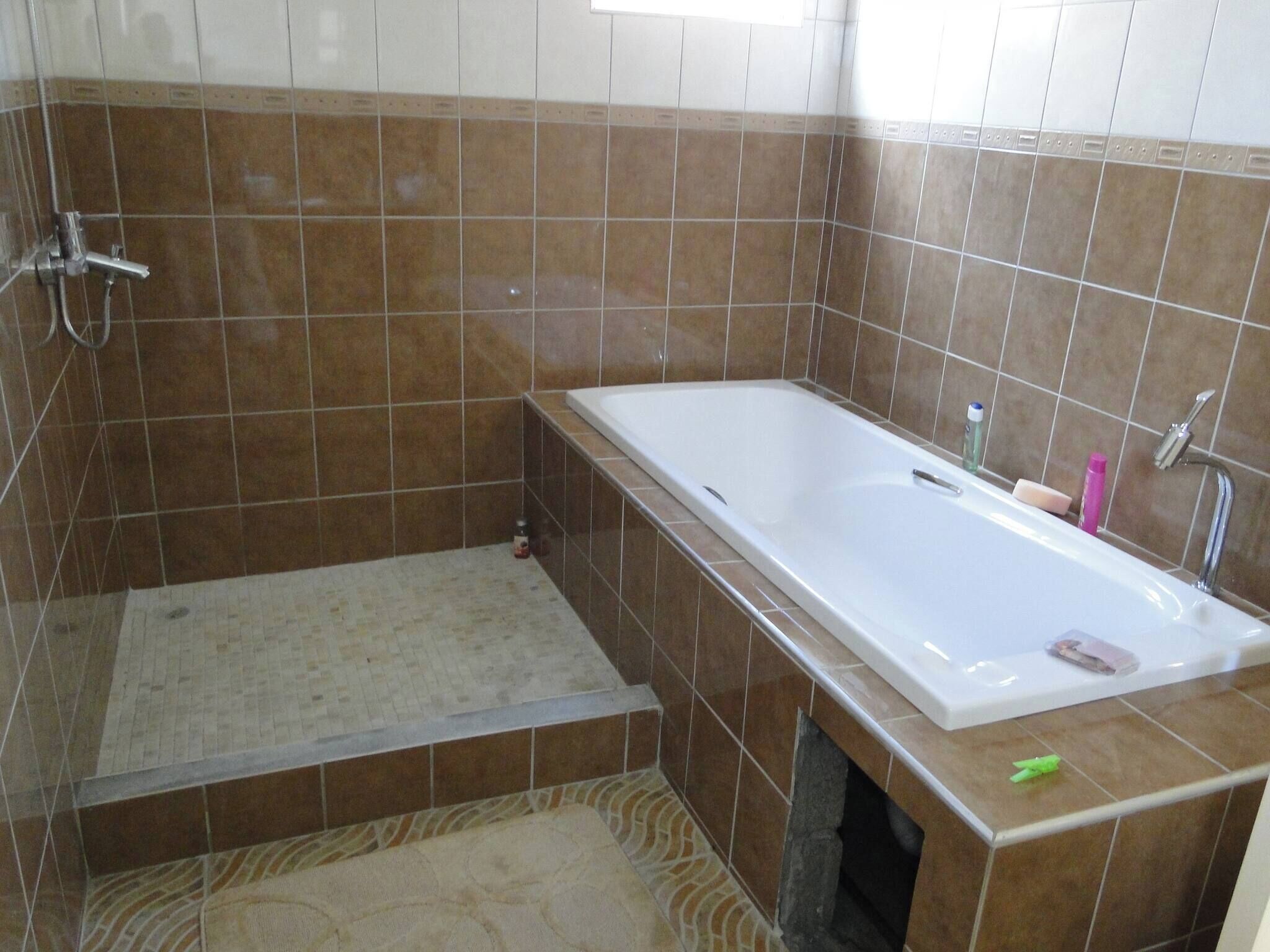 A bathroom with a bathtub, shower, and tiled walls.