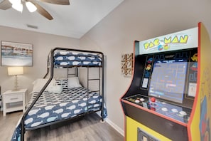 A room with a bunk bed, a Pac-Man arcade machine, a nightstand, and a lamp. - Hot Tub, Pool, Minutes to Busch Gardens: 3 King Beds, Mini Golf & More! (Tampa)