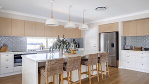 Une cuisine moderne dotée d’un îlot central, de meubles en bois, d’un réfrigérateur en acier inoxydable et d’un mur de fond en briques.