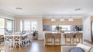 Une cuisine moderne dotée d’un îlot central, de tabourets de bar et de luminaires suspendus.