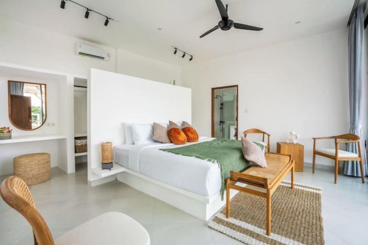 Un dormitorio moderno con cama, escritorio, silla, ventilador de techo y ventana.