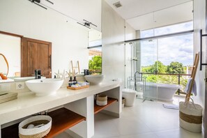 A modern bathroom with a large mirror, two sinks, a bathtub, and a shower. - Villa Ozkar - Elegant 3 Bedroom Villa with Pool & Sunset Terrace (Canggu)