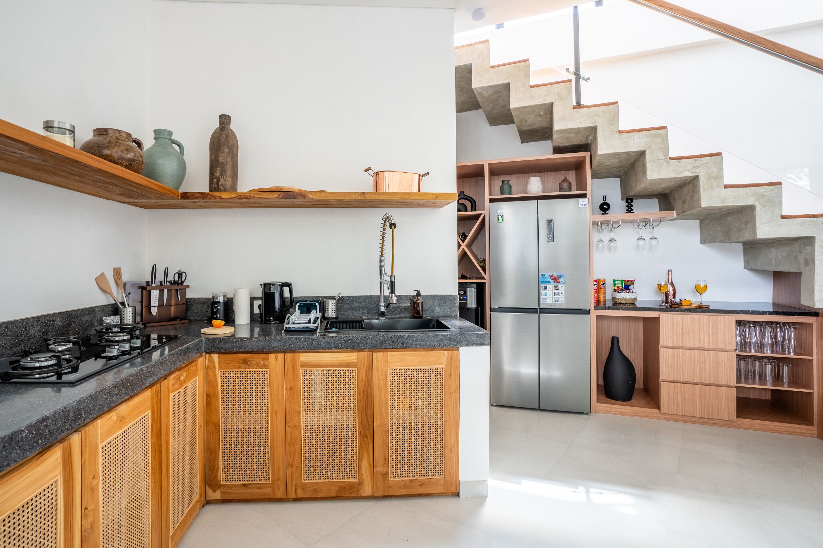 A modern kitchen with wooden cabinets, a stainless steel refrigerator, and a built-in stove.