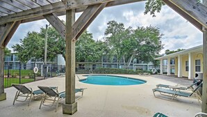 Et overdækket poolområde med liggestole og en træpergola.
