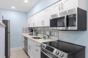 A modern kitchen with stainless steel appliances, white cabinetry, and patterned backsplash. - Caloosa Retreat- 2BR at Palmview Inn Sanibel (Sanibel)