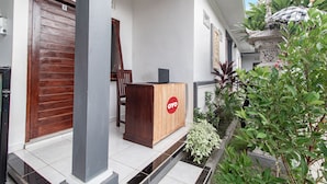 Un área de recepción con un mueble de madera que muestra la marca "OYO", una puerta de madera y un piso de baldosas.