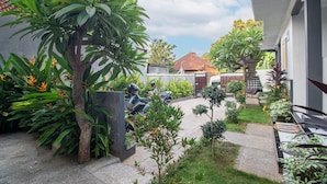 Un patio con diversas plantas, un banco de piedra y una motocicleta estacionada.