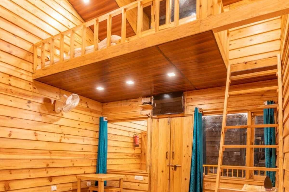 A wooden cabin with a bunk bed, a desk, and a ladder.